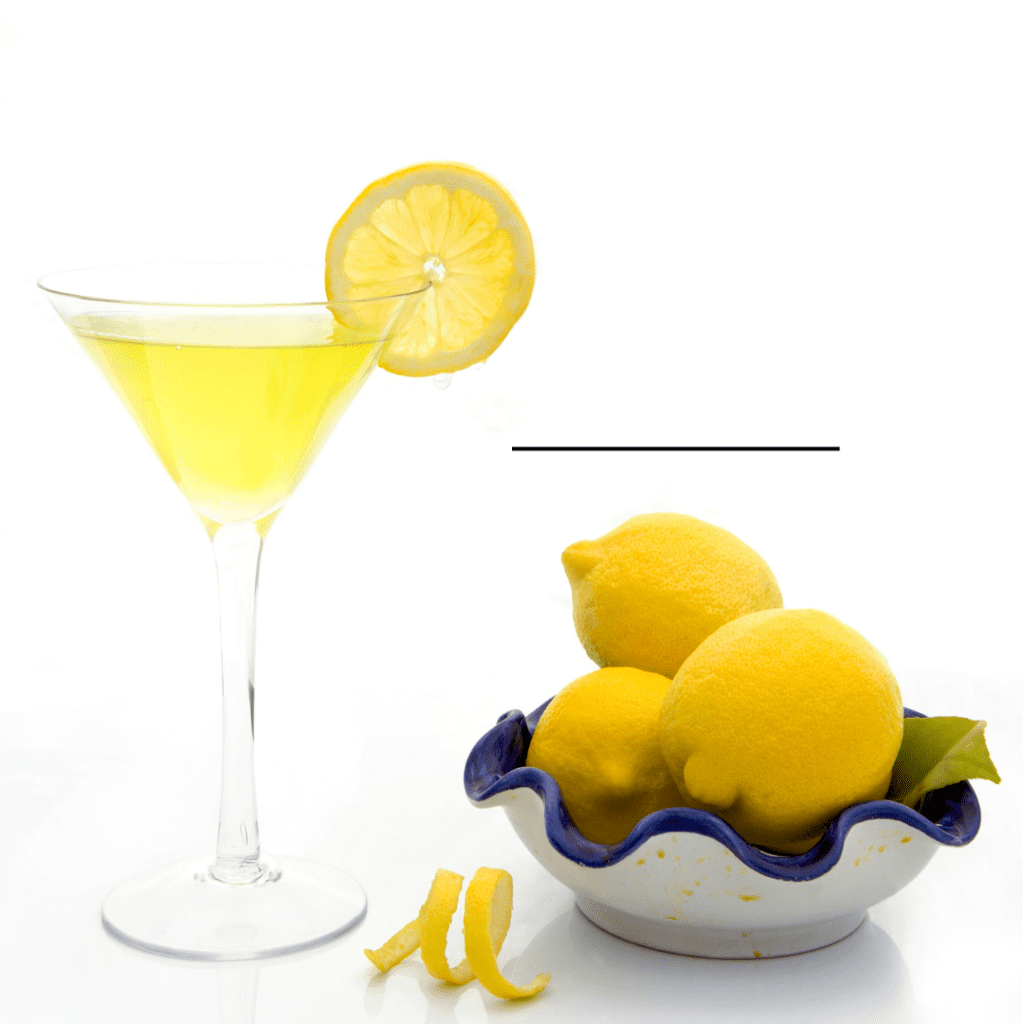 A glass of Lemon Drop Martini Limoncello with a bowl of lemons on the side.