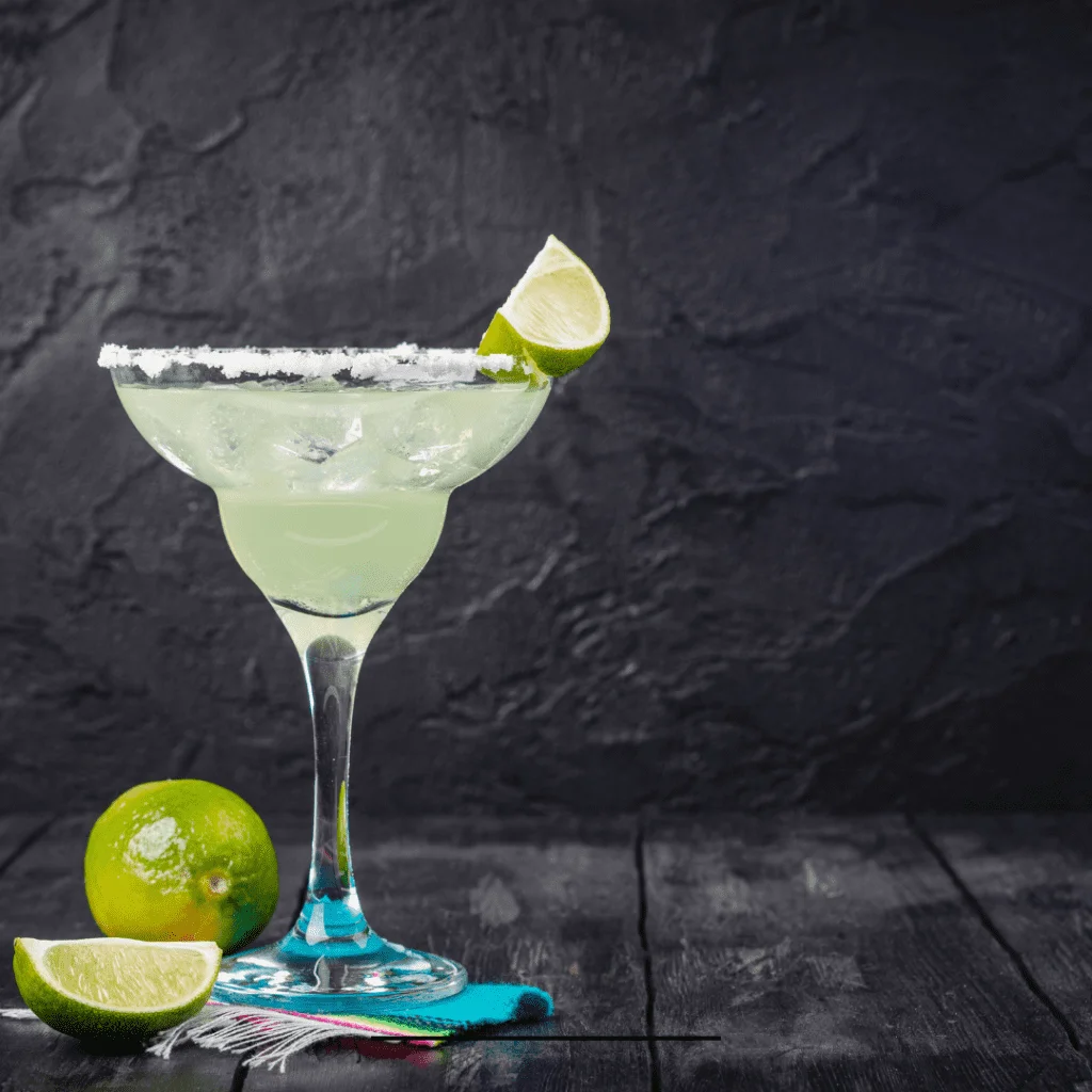 sour mix margarita topped with a slice of lemon and salted rim on a black background