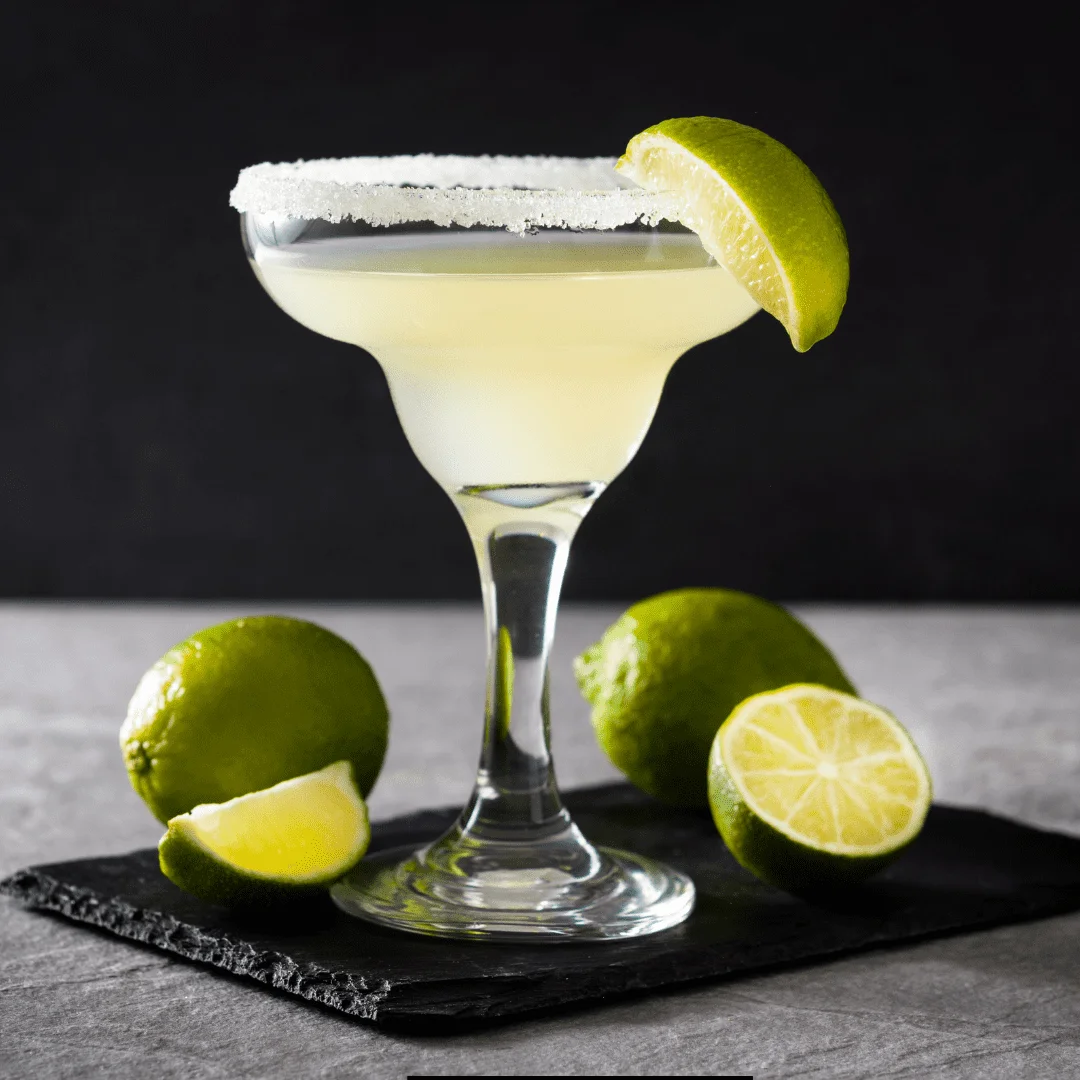 Margarita with lemon on top served on a black tray with lemons on side